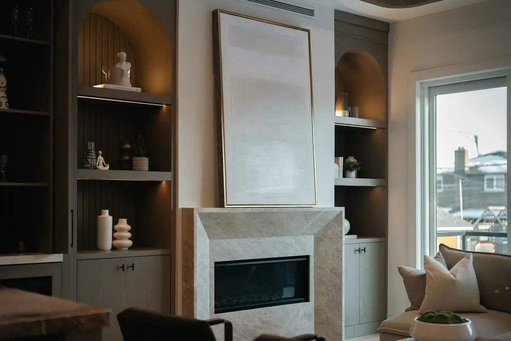 A living room with a fireplace and fitted shelving in the alcoves either side of the chimney breast.