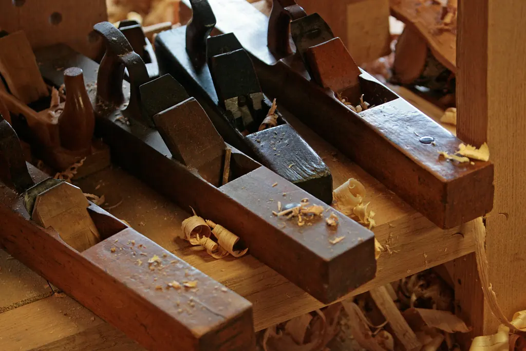 Three wooden hand planes on a workshop bench, with shavings around them.