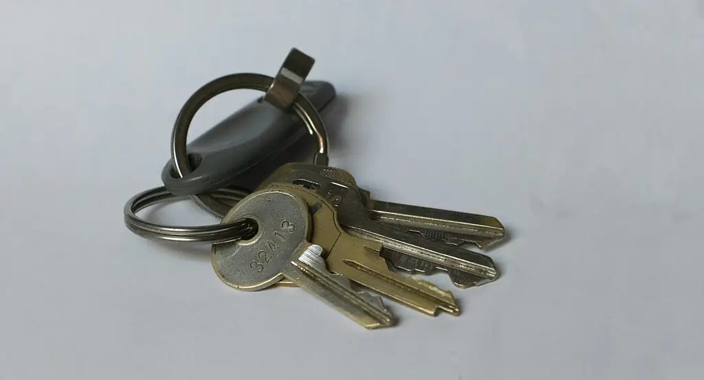 A bunch of brass and silver house keys on a pale grey surface.