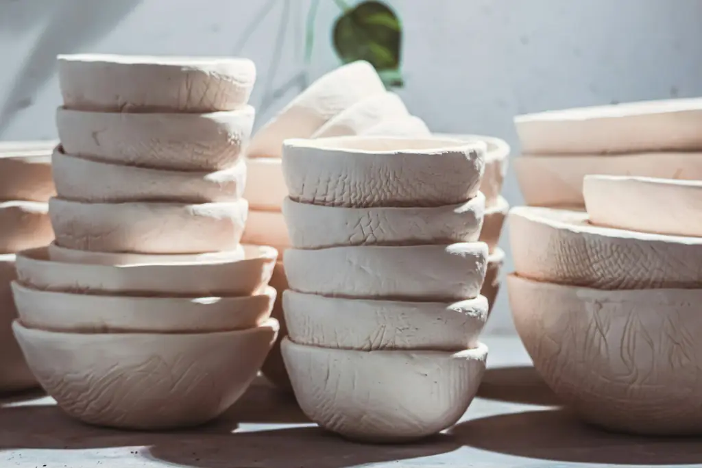 Stacks of unglazed, once-fired bowls on a studio table, waiting for glaze.